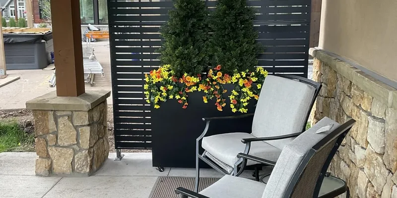 Metal privacy screen used beside outdoor seating and a planter